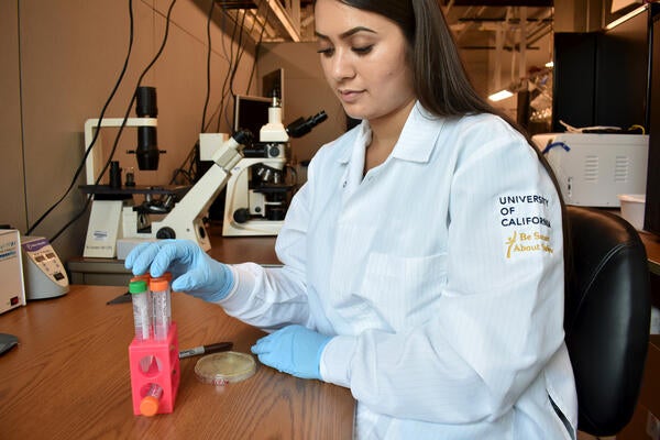 a young woman with long brown hair working in a lab