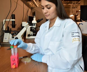 a young woman with long brown hair working in a lab